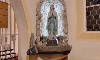 A statue of the Virgin Mary in a church, surrounded by stone masonry. The area is softly lit and provides a serene atmosphere. | © Unterwestegg-Kapelle Maria Hilf | Tanja Ritsch