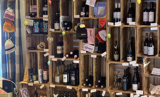 A wall of wooden shelves with various wine bottles and accessories. The shelves are decorative and some items are labeled. | © Uusziit | Chantal Kessler