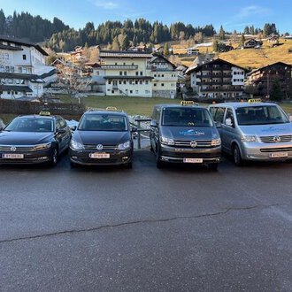 Zwei Taxis stehen vor einem Wohnhaus. Das schwarze Taxi und das weiße Kombi-Taxi sind bereit für Fahrgäste. | © Walser Taxi | Josef Düringer