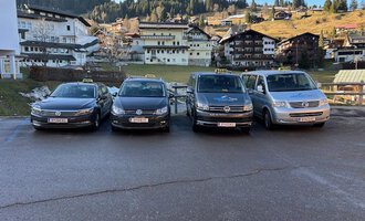 Zwei Taxis stehen vor einem Wohnhaus. Das schwarze Taxi und das weiße Kombi-Taxi sind bereit für Fahrgäste. | © Walser Taxi | Josef Düringer