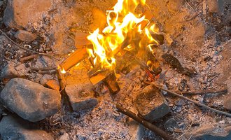 A cozy campfire in a stone circle. The flames glow brightly and create a warm atmosphere. | © Wildnisschule Kleinwalsertal