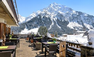 Eine Terrasse mit Tischen und Stühlen, umgeben von schneebedeckten Bergen. Der klare blaue Himmel sorgt für eine einladende Atmosphäre. | © Wirtshaus Hoheneck | Klaus Ruland