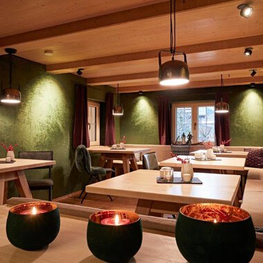 A stylish restaurant with wooden interiors and dim lighting. The tables are elegantly set, creating a cozy atmosphere.