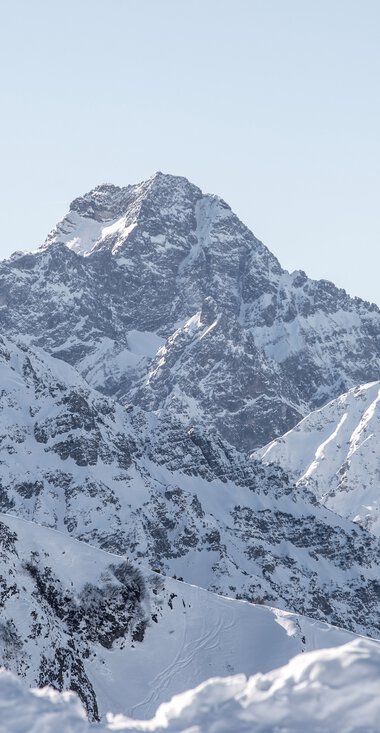 Panoramic view of the snow-covered Widderstein peak and surrounding mountains in winter scenery. | © Kleinwalsertal Tourismus eGen • Photographer: Dominik Berchtold
