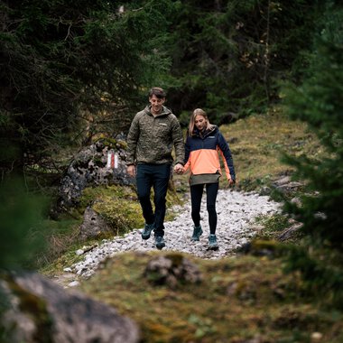 A couple walks hand in hand along a forest trail during daytime. | © Kleinwalsertal Tourismus eGen • Photographer: Hannah Bichay
