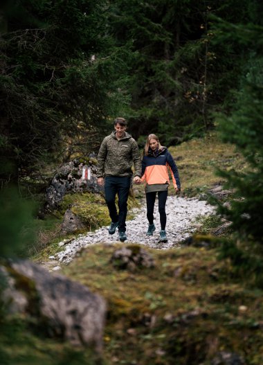 A couple walks hand in hand along a forest trail during daytime. | © Kleinwalsertal Tourismus eGen • Photographer: Hannah Bichay