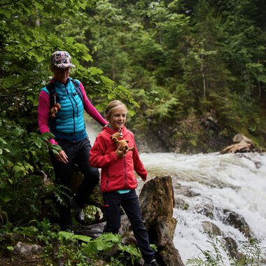Two people on a nature explorer adventure at Schwarzwasserbach in Kleinwalsertal, surrounded by green nature, one holding a frog. | © Kleinwalsertal Tourismus eGen • Photographer: Oliver Farys