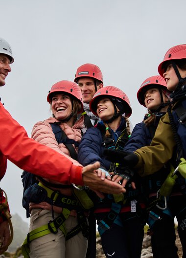 Group photo during a via ferrata adventure in the mountains, with a mountain guide greeting or welcoming the group.
