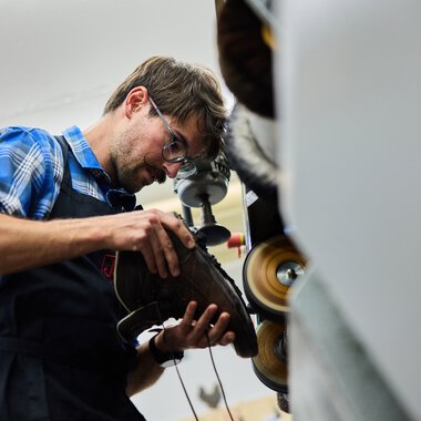 Man wearing safety glasses working with a machine in a workshop. | © Kleinwalsertal Tourismus eGen • Photographer: Oliver Farys