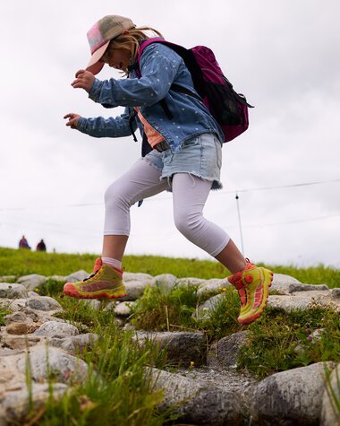 Girl children hiking in Kleinwalsertal, jumping over a rocky path during summer 2025. | © Kleinwalsertal Tourismus eGen • Photographer: Oliver Farys