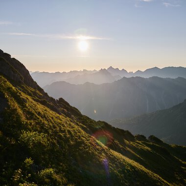 Landschaft im Kleinwalsertal bei Sonnenuntergang, mit Berge und grüne Hügel im Vordergrund. | © Kleinwalsertal Tourismus eGen • Fotograf: Oliver Farys