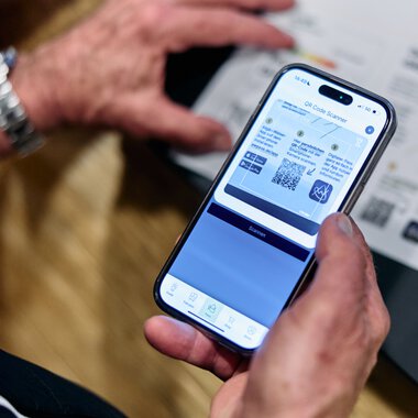Person scannt einen QR-Code auf einem Smartphone vor einer Registrierungsdokumentation im Kleinwalsertal. | © Kleinwalsertal Tourismus eGen • Fotograf: Oliver Farys