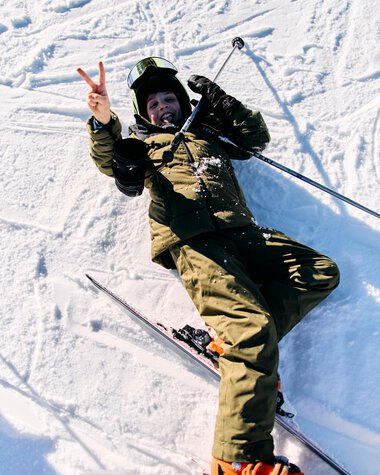 Child skiing in Kleinwalsertal, smiling and making a peace sign, dressed in winter gear on a snow slope. | © Kleinwalsertal Tourismus eGen • Photographer: Oliver Farys