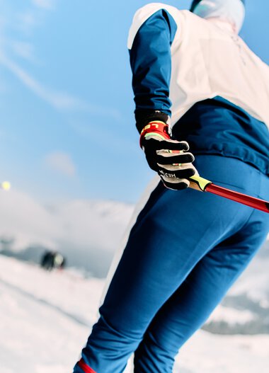 Skifahrer beim Langlauf in winterlicher Landschaft mit Schneebedeckten Bergen und blauem Himmel | ©  Kleinwalsertal Tourismus eGen • Fotograf: Oliver Farys