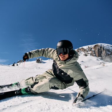 A skier skiing down a snowy mountain with a blue sky in the background. | © Kleinwalsertal Tourismus eGen • Photographer: Oliver Farys