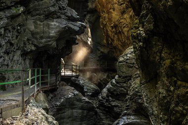 View into the narrow Breitach Gorge with rock walls and a walkway for exploration. | © Kleinwalsertal Tourismus eGen • Breitachklamm • Photographer: Dominik Berchtold
