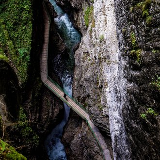 View from the Zwingsteig trail into the Breitach Gorge in summer, narrow gorge with water and rocks, surrounded by green vegetation. | © Kleinwalsertal Tourismus eGen • Breitachklamm • Photographer: Domink Berchtold