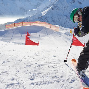 Skier on a slope in Oberstdorf with red gates and snowy mountain scenery. | © Kleinwalsertal Tourismus eGen • Oberstdorf Kleinwalsertal Bergbahnen