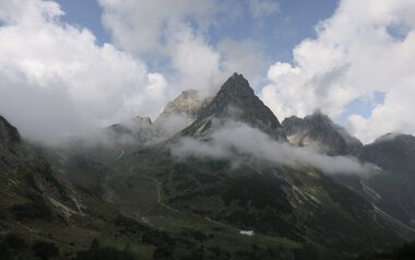 Berglandschaft mit schroffen Gipfeln, teilweise von Wolken bedeckt, in den Bergen. Eine beeindruckende Naturaufnahme. | © Kleinwalsertal Tourismus eGen • Fotograf: Antje Pabst