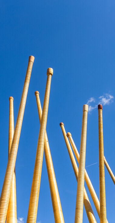 Bau von Holzblasinstrumenten, wahrscheinlich Alphörner, gegen einen blauen Himmel mit wenigen Wolken, bei einem Festival. | © Kleinwalsertal Tourismus eGen • Fotograf: Frank Drechsel