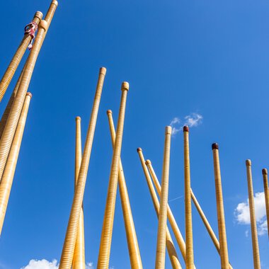 Bau von Holzblasinstrumenten, wahrscheinlich Alphörner, gegen einen blauen Himmel mit wenigen Wolken, bei einem Festival. | © Kleinwalsertal Tourismus eGen • Fotograf: Frank Drechsel